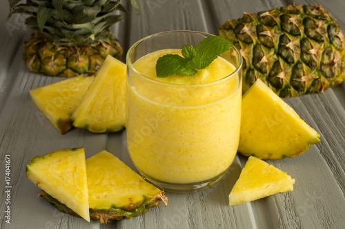 Pineapple smoothie and ingredient on the grey wooden background