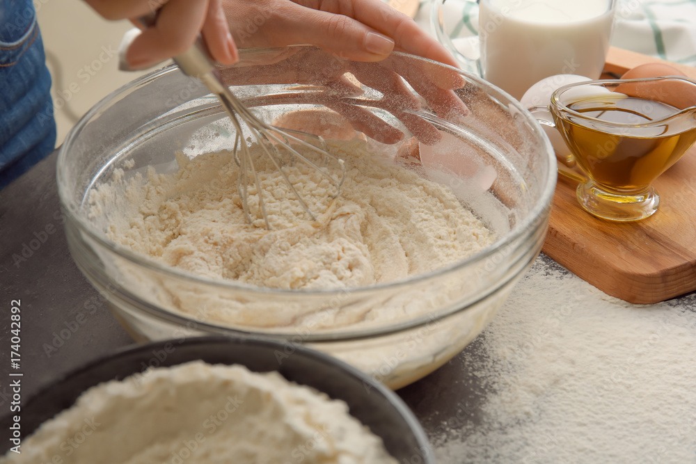 Female chef making dough in glass bowl on kitchen table Female chef making dough in glass bowl on kitchen table