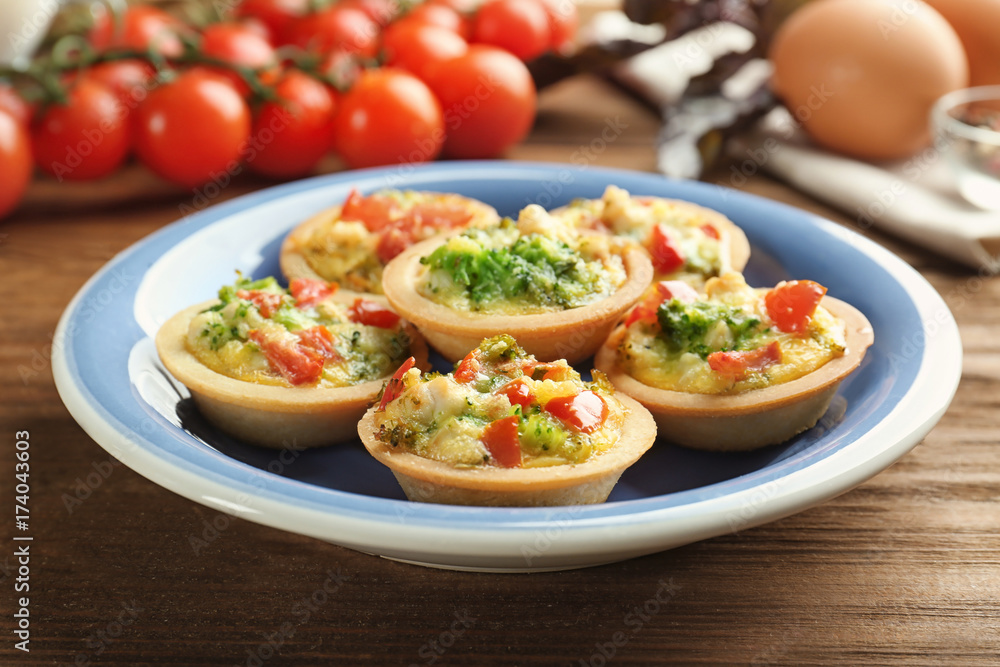 Plate with broccoli quiche tartlets on wooden table Plate with broccoli quiche tartlets on wooden table