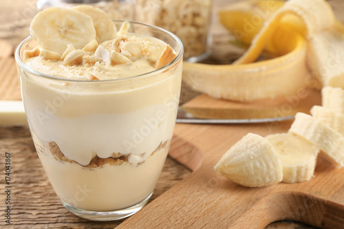 Glass with delicious banana pudding on table