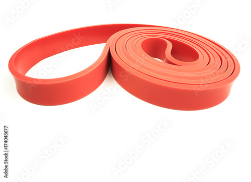 Red exercise resistance band on a white background with writing / copy space