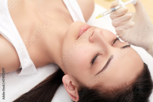 Hands of cosmetologist making injection in face, lips. Young woman gets beauty facial injections in salon. Face aging, rejuvenation and hydration procedures. Aesthetic cosmetology. Close up.