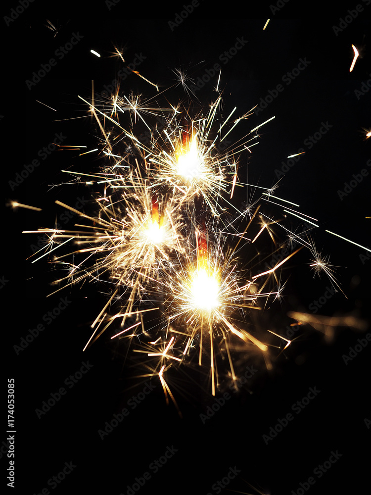 Festive background, bengal light on the dark background, New Year with sparklers sparks on a black background