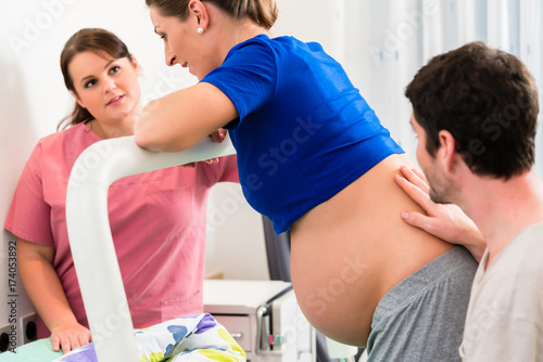 Canvas Print Woman laboring in delivery room with nurse and husband before birth