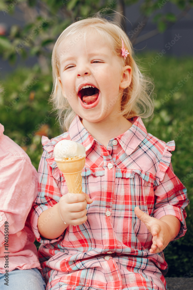 Portrait of cute white Caucasian blonde preschool girl with blue eyes in red pink shirt eating licking ice cream in waffle cone Portrait of cute white Caucasian blonde preschool girl with blue eyes in red pink shirt eating licking ice cream in waffle cone