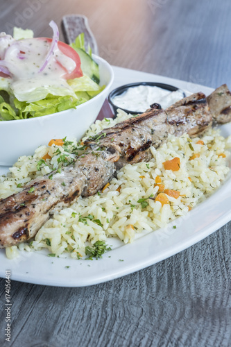 Greek Pork Soulaki Served on a Bed of Rice, Tzatziki Sauce and Salad photo