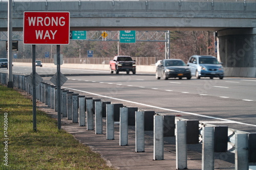 Wrong Way caution safety sign posted along a major interstate highway facing the opposite direction of traffic to avoid car vehicle collision accidents