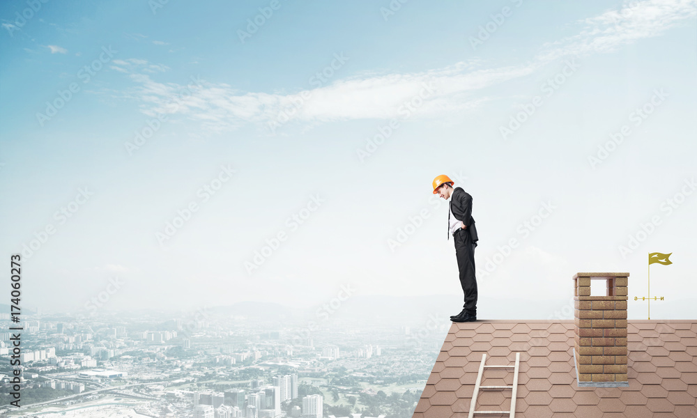 Businessman looking down from roof and modern cityscape at background. Mixed media Businessman looking down from roof and modern cityscape at background. Mixed media