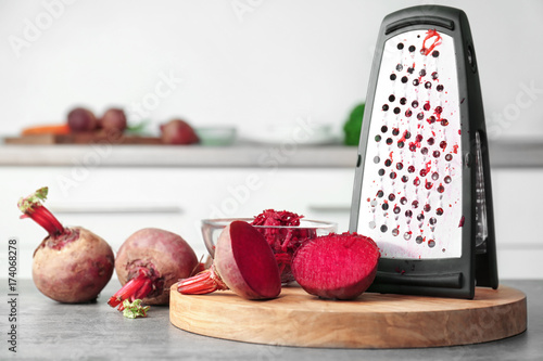 Foto Fresh beetroot and grater on table in kitchen