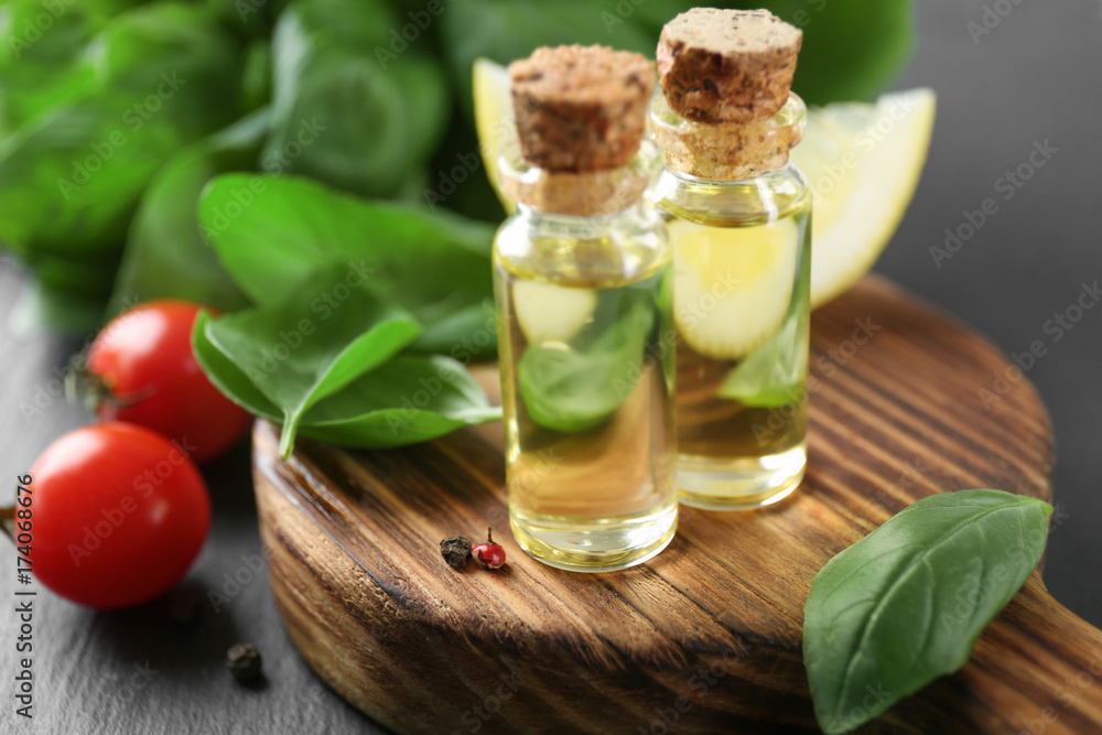 Bottles with basil oil and green leaves on wooden board Bottles with basil oil and green leaves on wooden board
