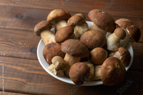 Plate of uncooked porcini mushrooms on wooden table