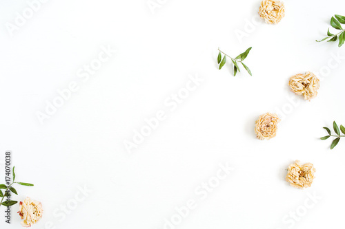 Flower border frame made of dry pastel beige roses on white background. Flat lay, top view. Floral texture background.