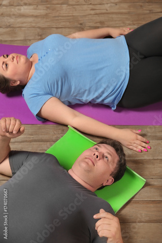 Overweight couple training together on wooden floor