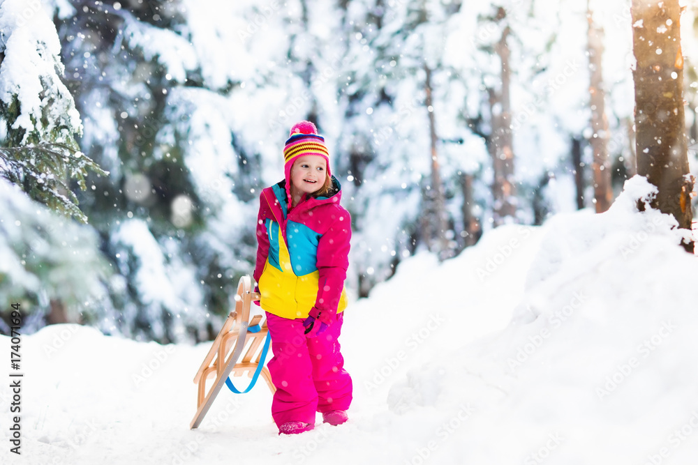 Child playing in snow on sleigh in winter park Child playing in snow on sleigh in winter park
