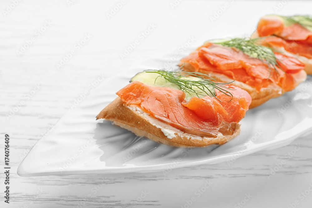 Tasty small sandwiches with salmon and cucumber on plate Tasty small sandwiches with salmon and cucumber on plate
