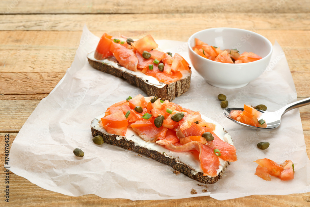 Tasty sandwiches with salmon and capers on paper Tasty sandwiches with salmon and capers on paper