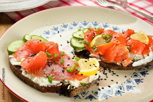 Tasty sandwiches with salmon and lemon on ornate plate