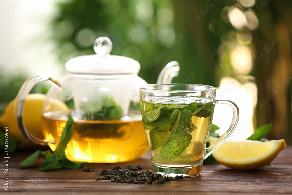 Teapot and cup with tasty mint tea on table Teapot and cup with tasty mint tea on table