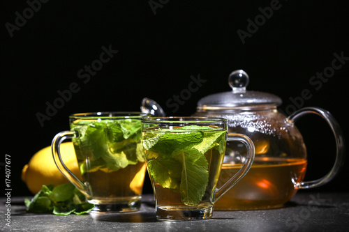 Cups with tasty mint tea on table