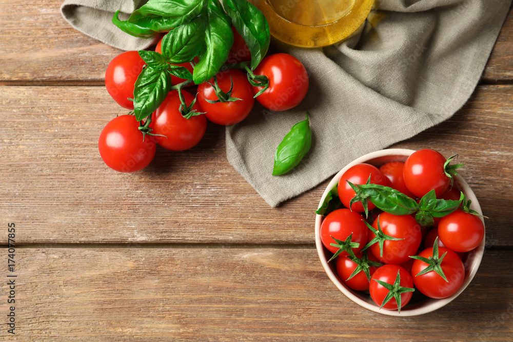 Composition with bowl of fresh cherry tomatoes on wooden table Composition with bowl of fresh cherry tomatoes on wooden table