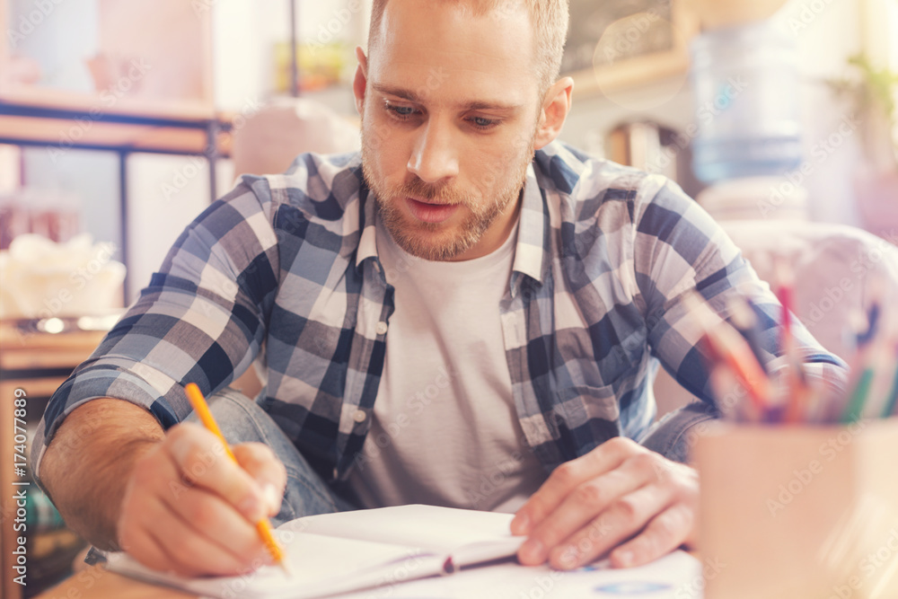 Handsome up and coming professional writing down his innovative ideas Handsome up and coming professional writing down his innovative ideas
