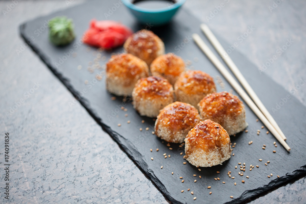 Japanese cuisine. Baked (hot) sushi with crab meat and cheese on a stone slab on a black granite background. Top view with copy space Japanese cuisine. Baked (hot) sushi with crab meat and cheese on a stone slab on a black granite background. Top view with copy space
