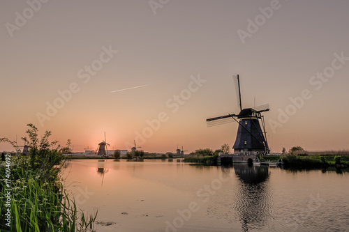 Travelling Concepts and Ideas. Picturesque Image of Historic Dutch Windmills In Front of The Canal Located in Traditional Village in Holland, The Netherlands. Shot at Kinderdijk During Golden Hour.