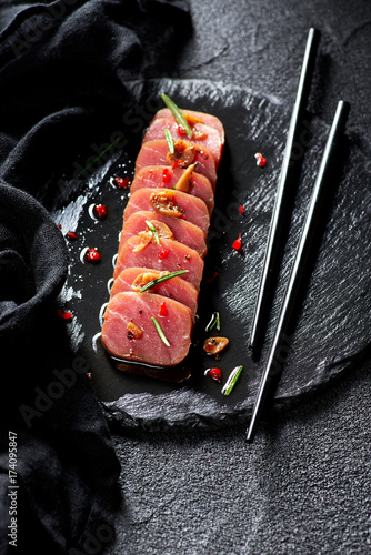 Obraz na płótnie Tuna steak in oil with chilli and rosemary on black slate plate w salonie