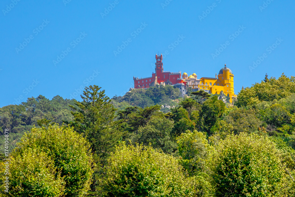 Aerial view of colorful Pena Palace on top of a hill above Sintra in sunny day, blue sky. Panorama of Palacio da Pena, a National Monument, Unesco Heritage and one of Seven Wonders of Portugal.
