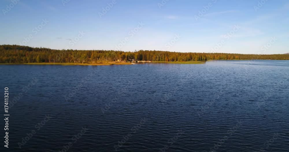 Northern lake, Cinema 4k aerial view just above the water level on lake pyhajarvi, infront of fjeld mountains and arctic taiga wilderess of Lapland, in Lappi, Finland