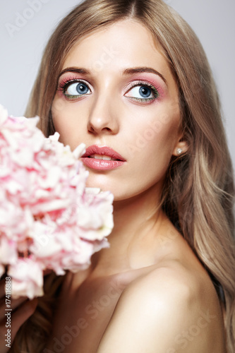 Closeup portrait of young beauty female face with blond hair and hydrangea bouquet flowers