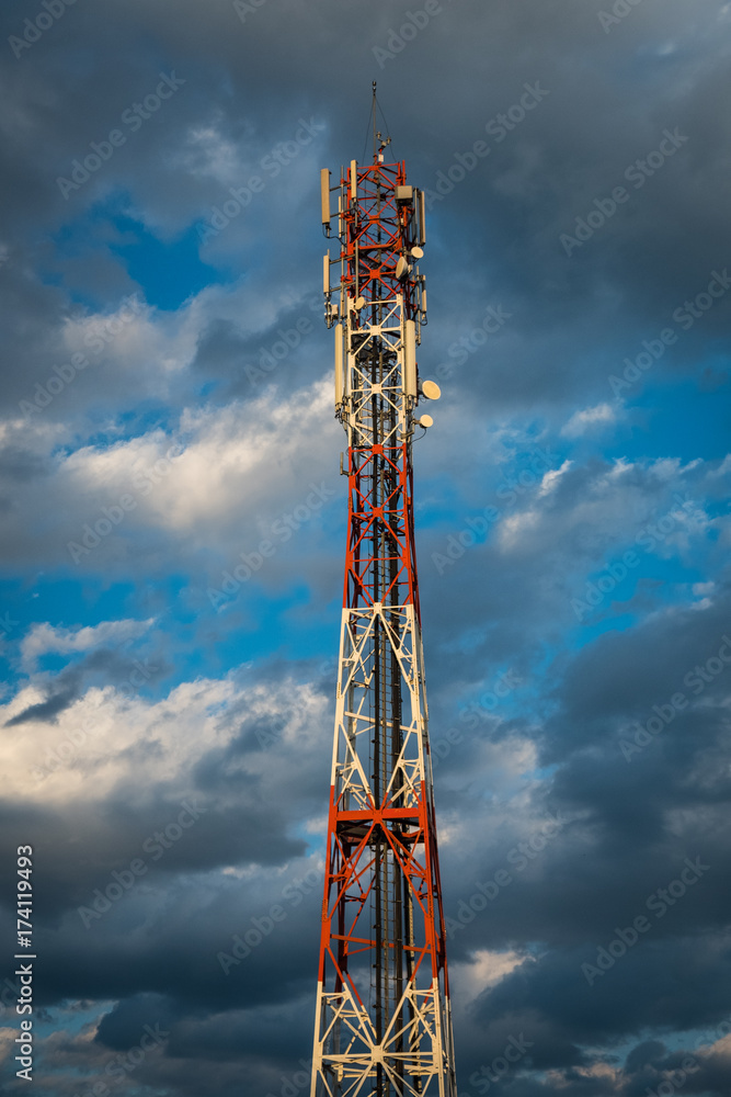 Mobile network antenna tower with cloudy sky in the background