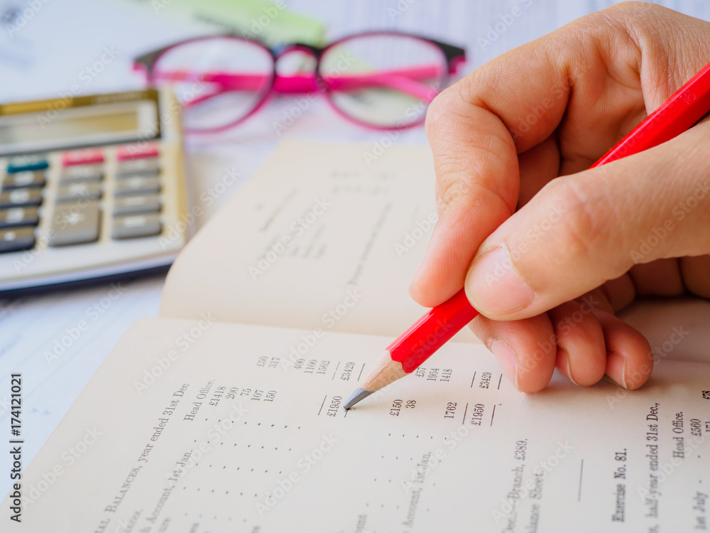 Closed up woman hand using calculator with note book and red pencil  in white background.