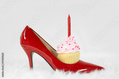 red high heel shoe on white fur with birthday cupcake