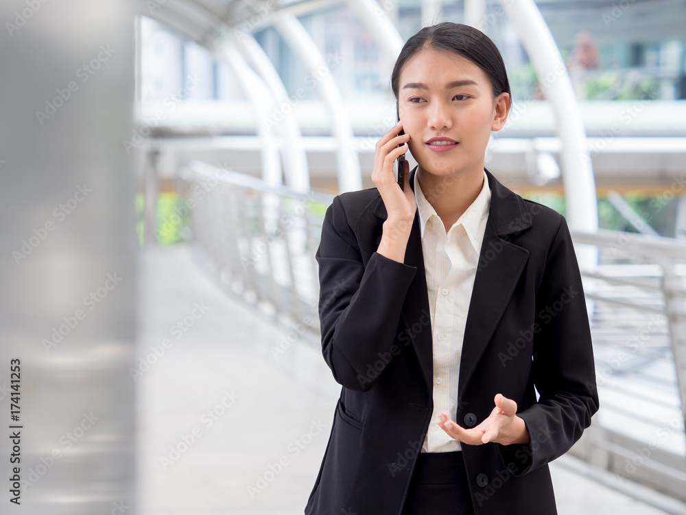 Portrait young Asian businesswoman 20-30s holding smart phone in formal suit at the modern city Portrait young Asian businesswoman 20-30s holding smart phone in formal suit at the modern city
