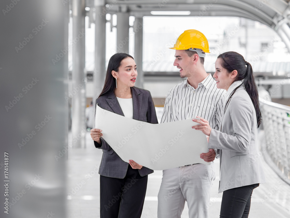 Young caucasian engineer/architect holding drawing/blueprint discuss with businesswoman for a project construction city building, happy feeling, positive, teamwork and togetherness concept Young caucasian engineer/architect holding drawing/blueprint discuss with businesswoman for a project construction city building, happy feeling, positive, teamwork and togetherness concept