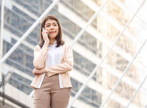 Portrait young Asian businesswoman holding smart phone in formal suit at the modern city, vintage tone