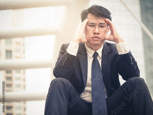 Upset asian businessman 40s tired from work sitting at stairs, unemployment, fired from job, disappointed, loss and feeling down concept
