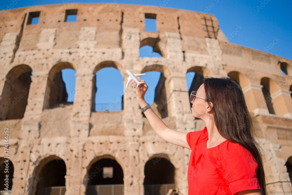 Young beautiful woman with small toy model airplane background Colosseum in Rome, Italy