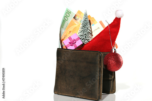 Christmas expenses. brown leather purse with santa claus cap, gift, fir tree and euro banknotes on white background with reflection. Christmas shopping. Holiday Sale