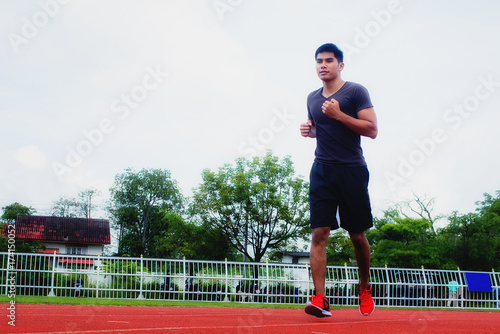 Young man jogging in the morning sun in the stadium.