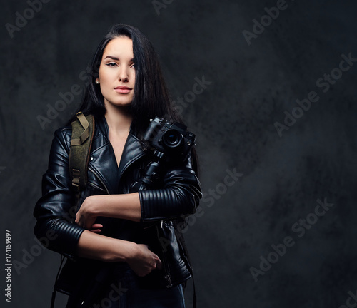 Brunette female photographer holds professional camera on a tripod.