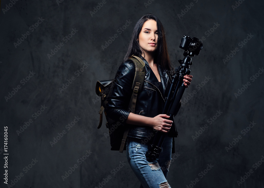 Brunette female photographer holds professional camera on a tripod.
