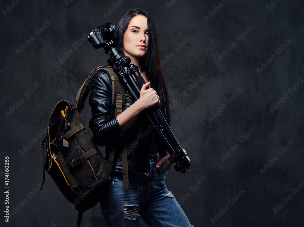 Brunette female photographer holds professional camera on a tripod.