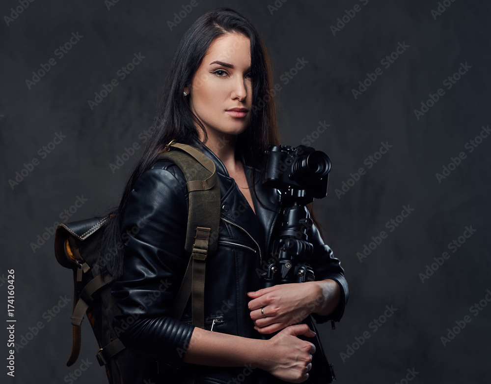 Brunette female photographer holds professional camera on a tripod.