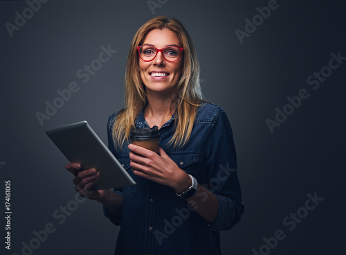 Blondy woman holds tablet PC and take away coffee cup.