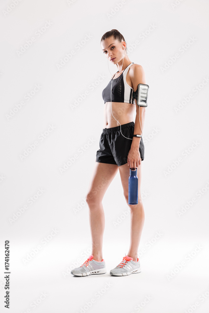 Full length portrait of an exhausted young sportswoman in earphones Full length portrait of an exhausted young sportswoman in earphones