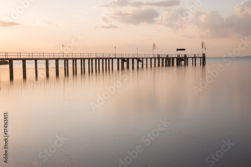 Long exposure view of a pier on a lake at sunset  with beautiful  warm tones and perfectly still water