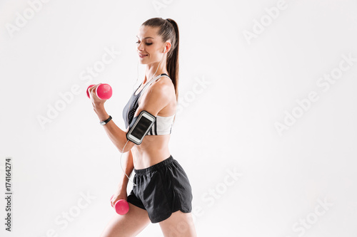 Portrait of a happy fitness woman in sportswear listening to music