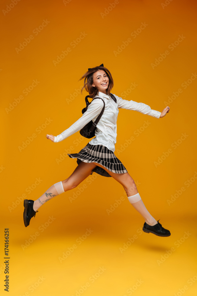 Full length portrait of a smiling cheerful schoolgirl in uniform